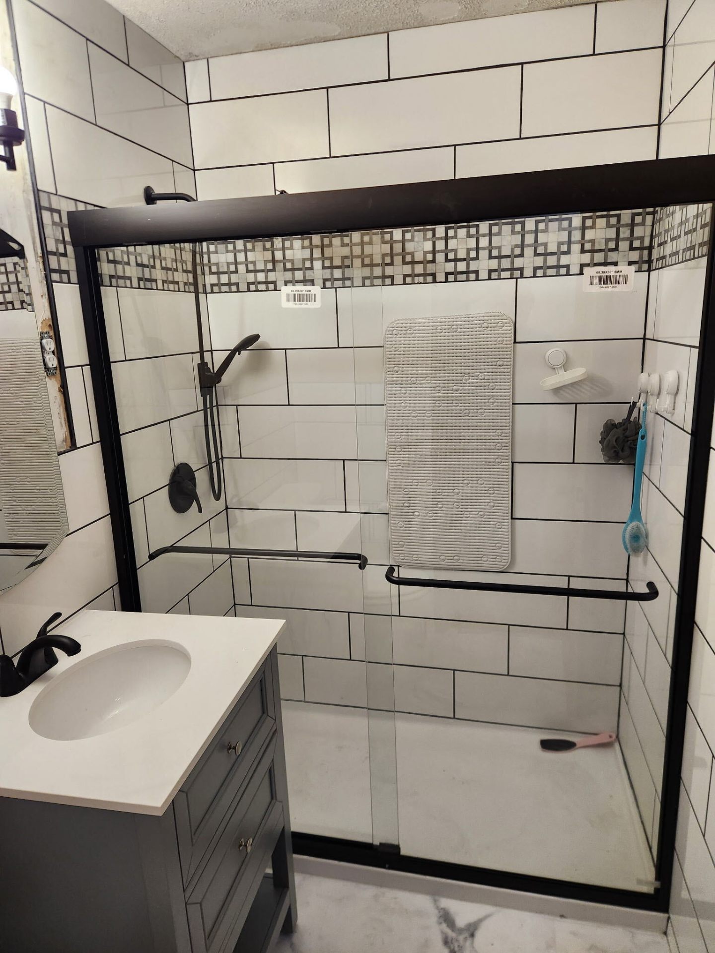 Bathroom remodel with white subway tile shower surround and mosaic accent band